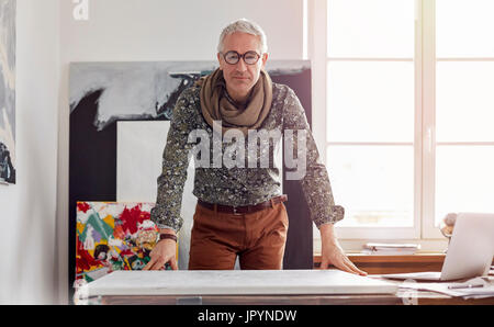 Zuversichtlich männlichen Porträtfotografin stehend über Leinwand im Atelier Stockfoto