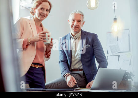 Porträt, Lächeln, zuversichtlich Geschäftsleute Kaffee trinken und arbeiten am Laptop im Büro Stockfoto
