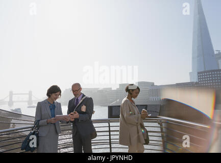 Geschäftsleute, die mit digital-Tablette im sonnigen städtischen Waterfront, London, UK Stockfoto