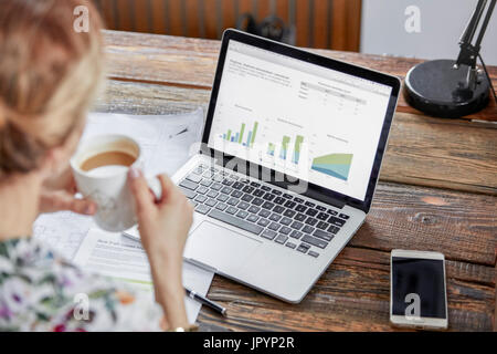 Geschäftsfrau, Tee trinken und Überprüfung der Daten auf laptop Stockfoto