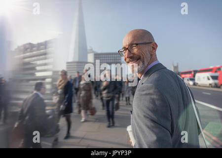 Porträt lächelnd Geschäftsmann zu Fuß, auf belebten städtischen Bürgersteig, London, UK Stockfoto