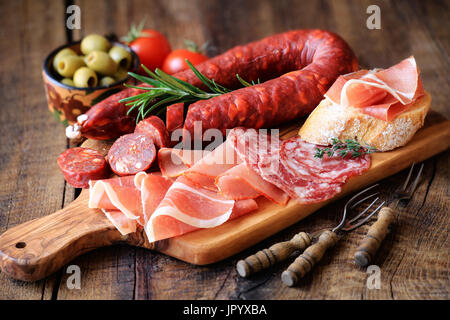 Wurst-Platte mit traditionellen spanischen Tapas - Chorizo, Salsichon, Jamon Serrano, Lomo - Trajine auf Holzbrett mit Oliven und Brot Stockfoto