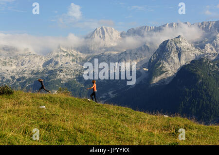 Junge springen beim Wandern mit seiner Mutter, das Hochland von Montasio, Julische Alpen, Friaul Julisch Venetien, Italien. Stockfoto