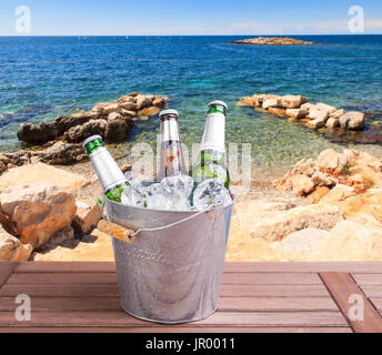 Drei ungeöffnete Flaschen Bier im Eiskübel auf Strand Hintergrund Stockfoto