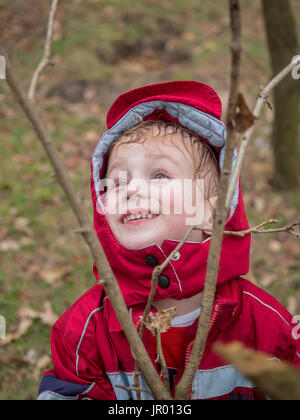 Der kleine Junge in einer roten Jacke im Wald Stockfoto