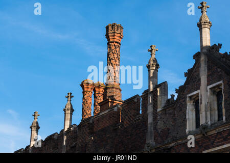 Detail der Schornsteine und Brüstung entlang des oberen Randes eine Tudor Gebäude Außenwand mit Fenster und Ornamente Stockfoto