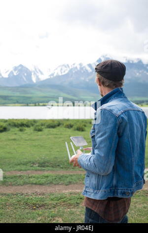 Mann-Controlling eine Drohne auf Gebirgshintergrund. Stockfoto