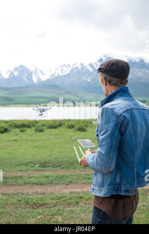 Mann-Controlling eine Drohne auf Gebirgshintergrund. Stockfoto