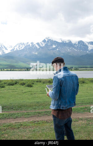 Mann-Controlling eine Drohne auf Gebirgshintergrund. Stockfoto