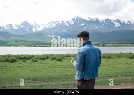 Mann-Controlling eine Drohne auf Gebirgshintergrund. Stockfoto