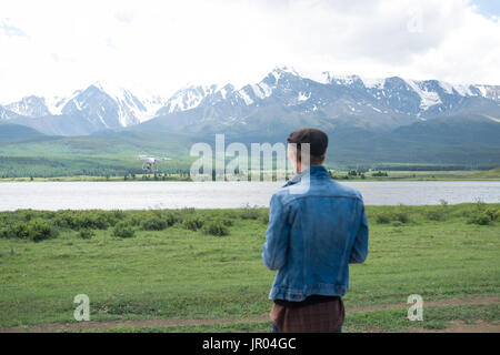 Mann-Controlling eine Drohne auf Gebirgshintergrund. Stockfoto