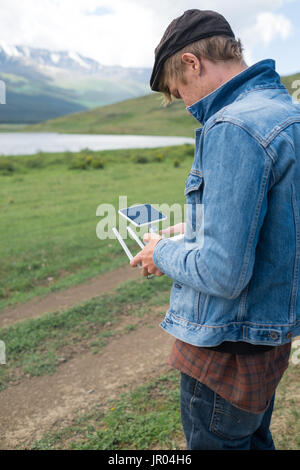 Mann-Controlling eine Drohne auf Gebirgshintergrund. Stockfoto