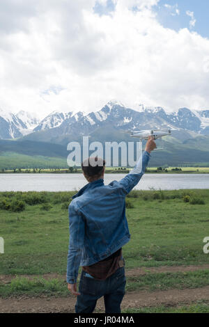 Mann-Controlling eine Drohne auf Gebirgshintergrund. Stockfoto