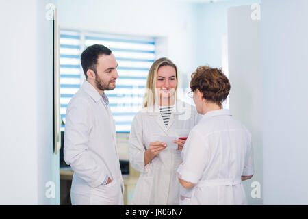 Reife Arzt mit Krankenschwestern in einem Krankenhaus Flur zu diskutieren. Arzt Patienten Fall Stand mit seinem medizinischen Stab nach Operation zu erörtern. Stockfoto