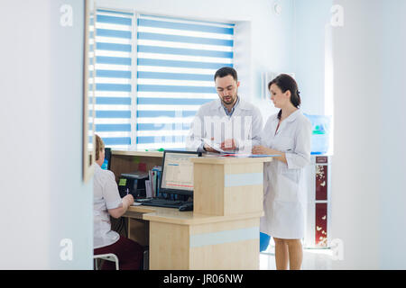 Beschäftigt Empfang in einem Krankenhaus mit Ärzten und Personal an der Rezeption Stockfoto