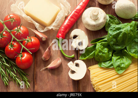 TISCHPLATTE GEFÜLLT MIT VERSCHIEDENEN FRISCHEN ITALIENISCHEN ZUTATEN: BASILIKUM, KRÄUTER, TOMATEN, PARMESAN-KÄSE, IN SCHEIBEN GESCHNITTENEN MOZZARELLA, GETROCKNETE PILZE, VERSCHIEDENE GETROCKNETE PASTA, SONNENGETROCKNETE TOMATEN Stockfoto