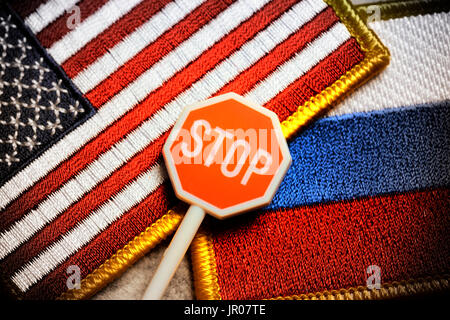 Stop-Schild vor Fahnen der USA und Russland, US-Sanktionen Stockfoto