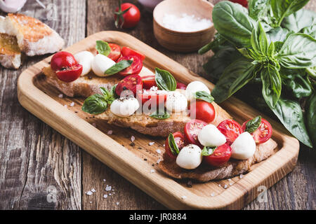 Hausgemachte Caprese Bruschetta mit geschmackvollen Kirschtomaten, frischem Basilikum und Mozzarella auf geröstetem Brot Stockfoto