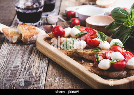 Hausgemachte Caprese Bruschetta mit geschmackvollen Kirschtomaten, frischem Basilikum und Mozzarella auf geröstetem Brot Stockfoto