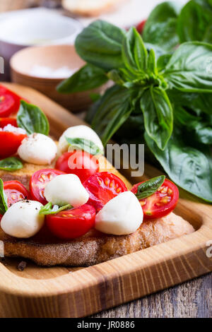 Hausgemachte Caprese Bruschetta mit geschmackvollen Kirschtomaten, frischem Basilikum und Mozzarella auf geröstetem Brot Stockfoto