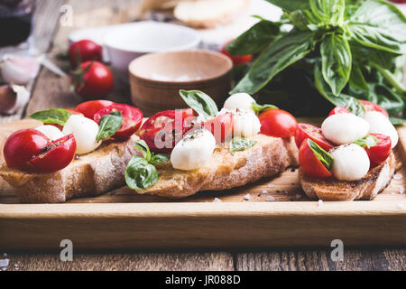 Hausgemachte Caprese Bruschetta mit geschmackvollen Kirschtomaten, frischem Basilikum und Mozzarella auf geröstetem Brot Stockfoto