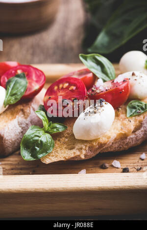 Hausgemachte Caprese Bruschetta mit geschmackvollen Kirschtomaten, frischem Basilikum und Mozzarella auf geröstetem Brot Stockfoto