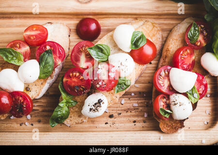 Hausgemachte Caprese Bruschetta mit geschmackvollen Kirschtomaten, frischem Basilikum und Mozzarella auf geröstetem Brot Stockfoto