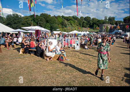 Familien genießen die Sonne sitzen, trinken und Essen draußen Zelte und Festzelte am Hafen Eliot Festival Cornwall UK Stockfoto