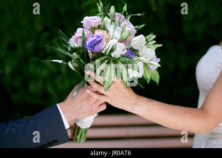 Bräutigam gibt der Braut einen Brautstrauß Stockfoto