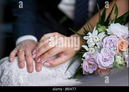 Hände der Braut und des Bräutigams in der Nähe von den Brautstrauß für einen Spaziergang Stockfoto
