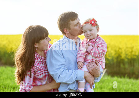 Mama und Papa und Tochter gehen auf die grünen Sommerwiese Stockfoto