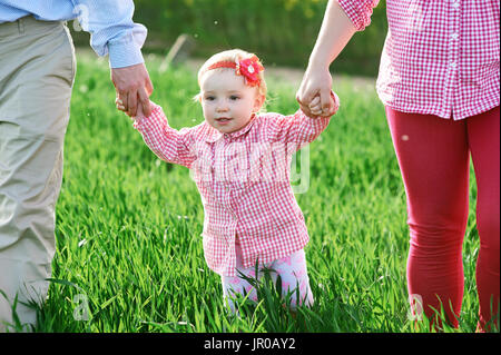 Mama und Papa und Tochter gehen auf die grünen Sommerwiese Stockfoto