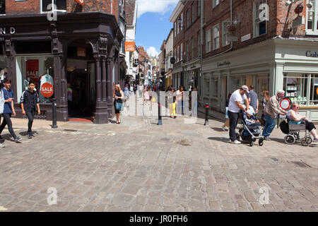 Eine beschäftigt Straßenszene in York in der Nähe von Stonegate mit Geschäften, Kneipen und Menschen unter einem blauen Sommerhimmel Stockfoto