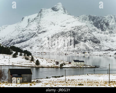 Robuste, erreichte Berge mit Schnee bedeckt und ruhigen Wasser entlang der Küste, Lofoten, Nordland, Norwegen Stockfoto