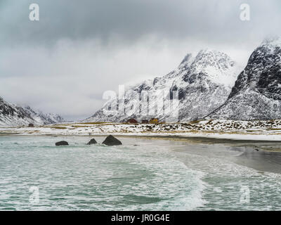 Landschaft der Küste und Robuste, schneebedeckte Berge, die unter einem bewölkten Himmel, Lofoten, Nordland, Norwegen Stockfoto