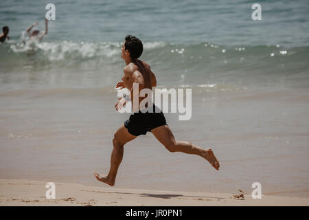 Junger Mann In Fitnesskleidung Strand entlang laufen Stockfoto