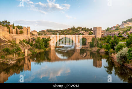 Wunderschöne Landschaft von Toledo in Spanien. Steinerne Brücke in ruhiger Fluss. Blaue Himmel spiegelt sich im kristallklaren Wasser. Große Festung und das Land befindet sich auf der Rückseite Stockfoto