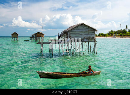 Semporna, Malaysia - 18. April 2015: Young Bajau Laut junge paddeln ein Boot in der Nähe von gestelzt Häuser aus der Küste Borneos in der Celebes-See in der Vicini Stockfoto