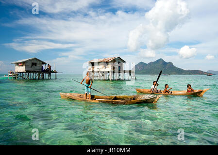 Semporna, Malaysia - 18. April 2015: Young Bajau Laut junge paddeln ein Boot in der Nähe von gestelzt Häuser aus der Küste Borneos in der Celebes-See in der Vicini Stockfoto