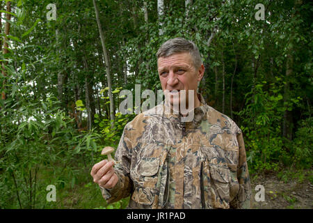 Der Mann einen kleinen Pilz im Wald gefunden und war sehr überrascht Stockfoto