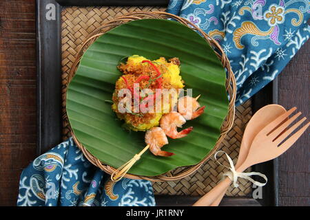 Ketan Serundeng Udang. Gelbwurz Klebreis mit Roasted Coconut und Garnelen Satay Stockfoto