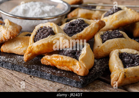 Appetitliche Brötchen mit Mohn und Rosinen. Hamantashen/Hamantash - traditionelle jüdische süße Nahaufnahme auf dem Tisch. Horizontale Stockfoto