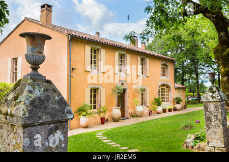 Altes Landhaus aus Stein, umgeben von ruhigen Gärten in Südfrankreich mit antikem Pfosten im Vordergrund Stockfoto