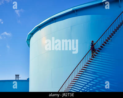 Ein Händler Climgs die Treppe von einem großen, blauen Behälter in einer Raffinerie; Edmonton, Alberta, Kanada Stockfoto