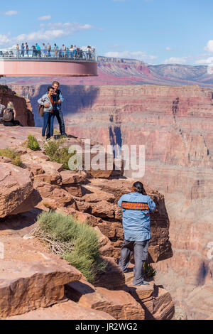 Ein indianischer Arbeiter fotografiert Touristen am Skywalk Viewpoint über dem West Grand Canyon Natural Landscape Area in Arizona, Eine beliebte Tour... Stockfoto