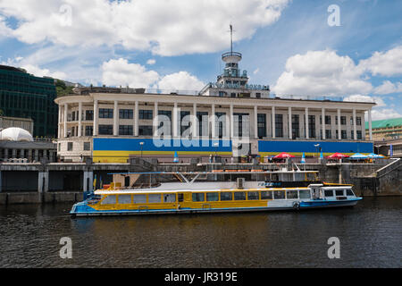 KIEW, UKRAINE - 12. JUNI 2016: Ausflugsboot vor dem Hafengebäude am Kiewer Fluss am Dnjepr (Dnipro) im Podil-Distrikt Stockfoto