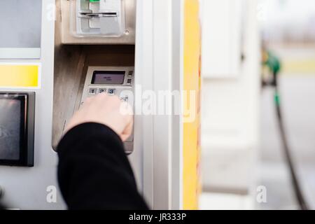 Frau Kraftstoff auf Self-Service-Tankstelle mit Kreditkarte bezahlen. Pin-Code Eingabe Stockfoto