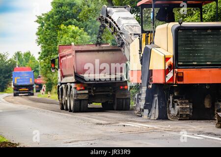 Straßenarbeiten. Asphalt entfernen Maschine laden in Pulverform Asphalt auf dem LKW Stockfoto