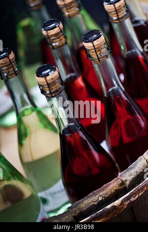 Rot- und Weißweine in Flaschen auf einem Fass Stockfoto