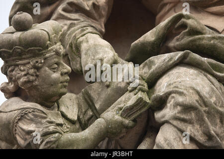 Junge St. Wenceslaus lernt lesen, die von seiner Großmutter St. Ludmila von Böhmen gelehrt. Detail der barocken Statue der Heiligen Ludmila und St. Wenzel auf der Karlsbrücke in Prag, Tschechische Republik. Die ursprüngliche Statue von 1720 geschnitzt in der Werkstatt des österreichisch-böhmischen Barock-Bildhauer Matthias Bernhard Braun wurde am Anfang des 21. Jahrhunderts durch eine Kopie ersetzt. Stockfoto